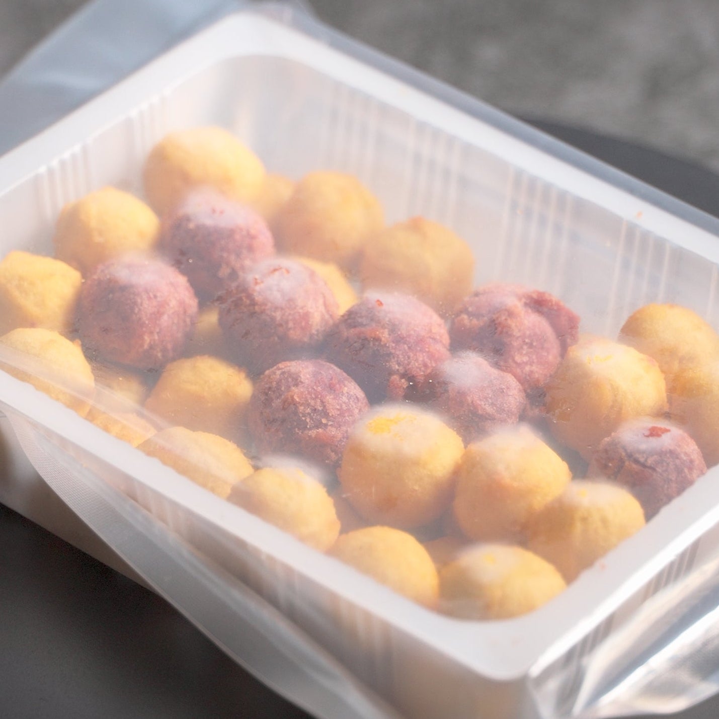 Frozen sweet potato balls sealed inside a vacuum tray package.