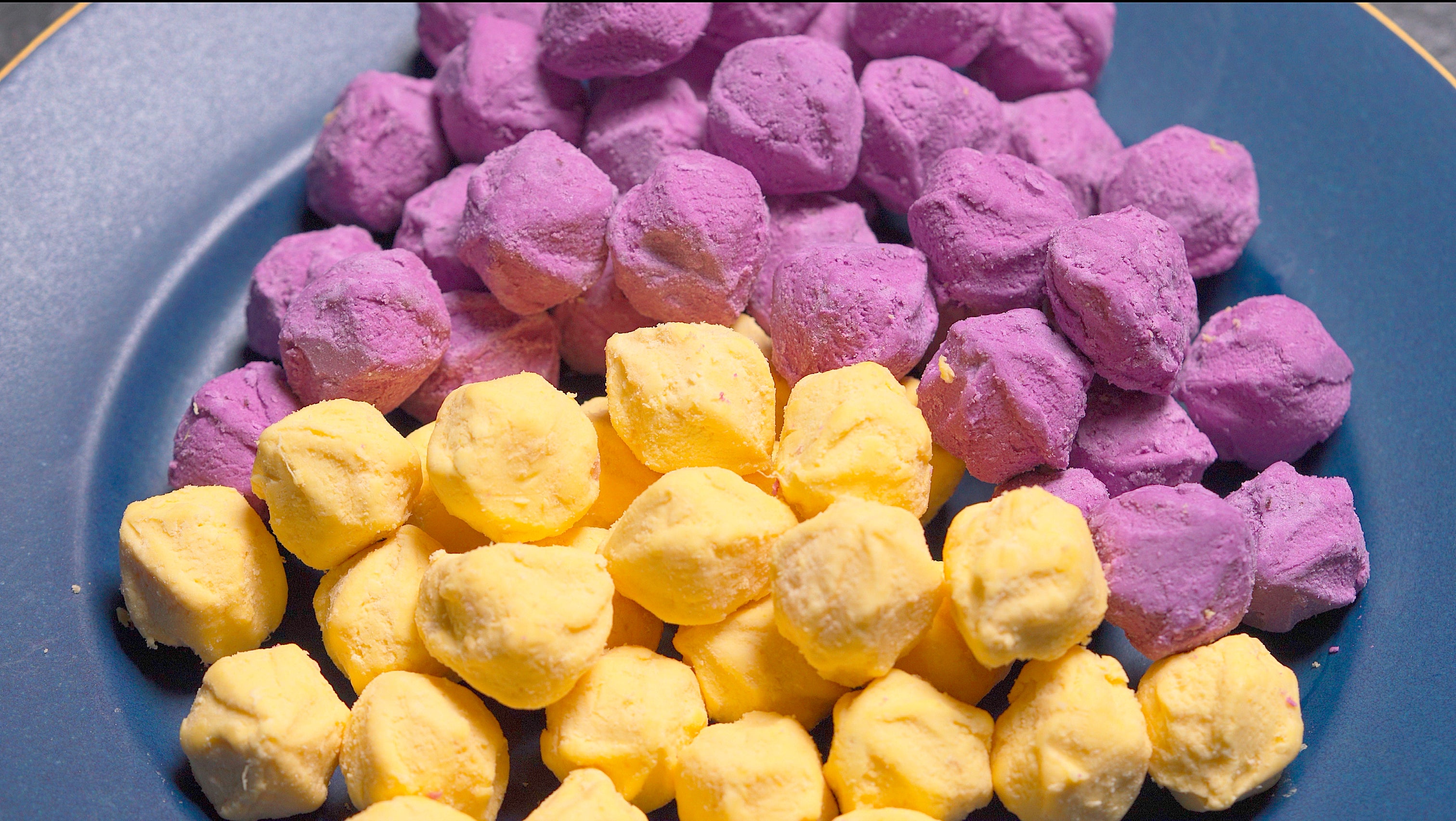 Purple and yellow sweet potato balls displayed on a plate.