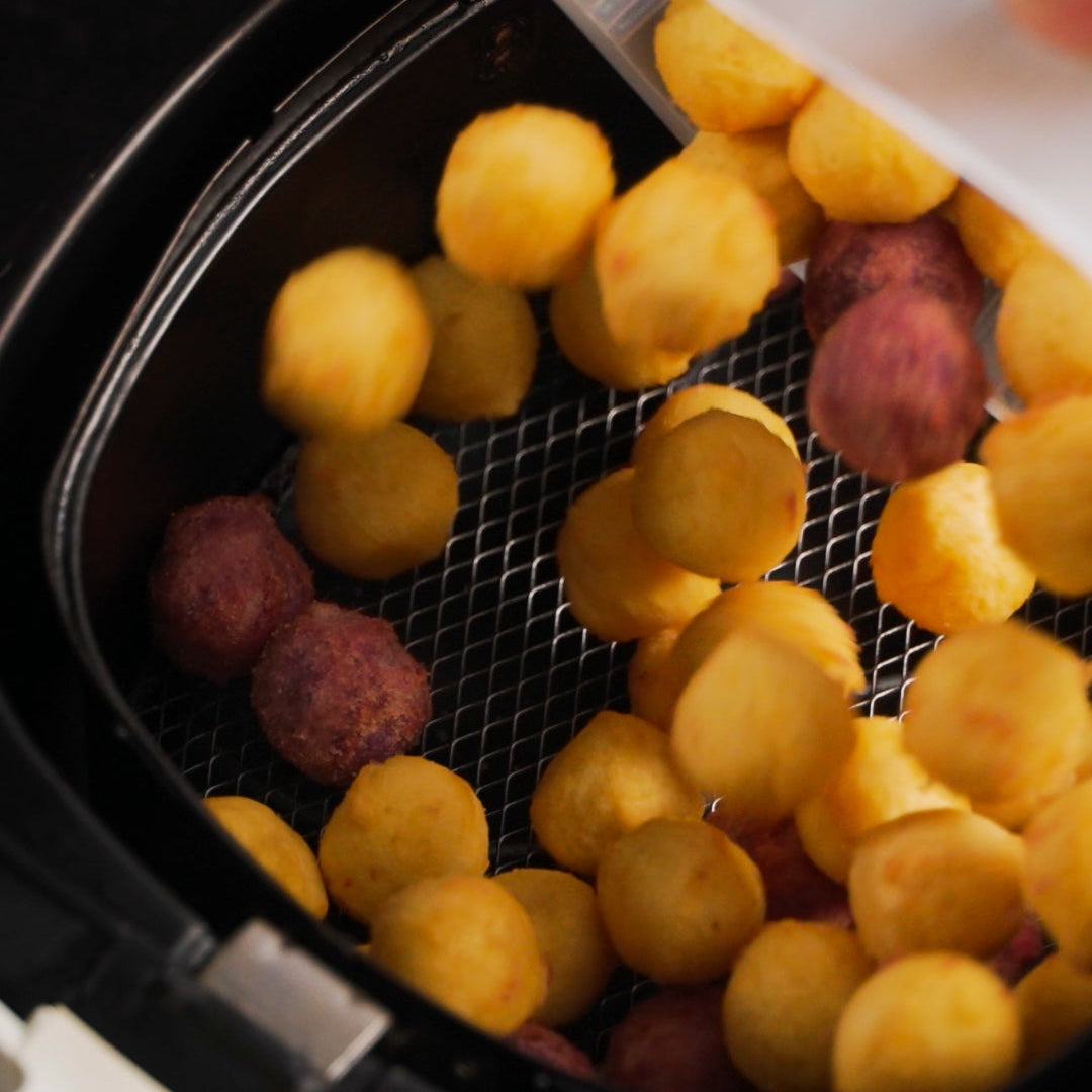 Lumo sweet potato balls being loaded into air fryer basket.