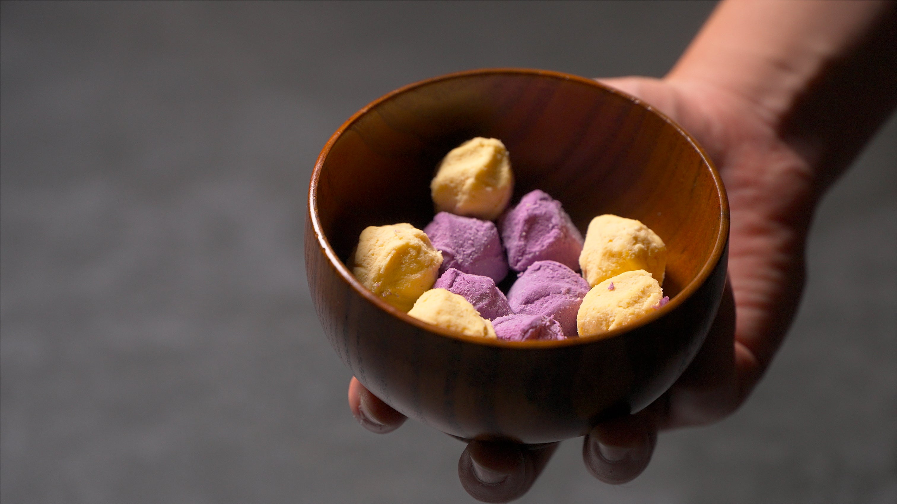 Frozen purple and yellow sweet potato balls served in a wooden bowl.